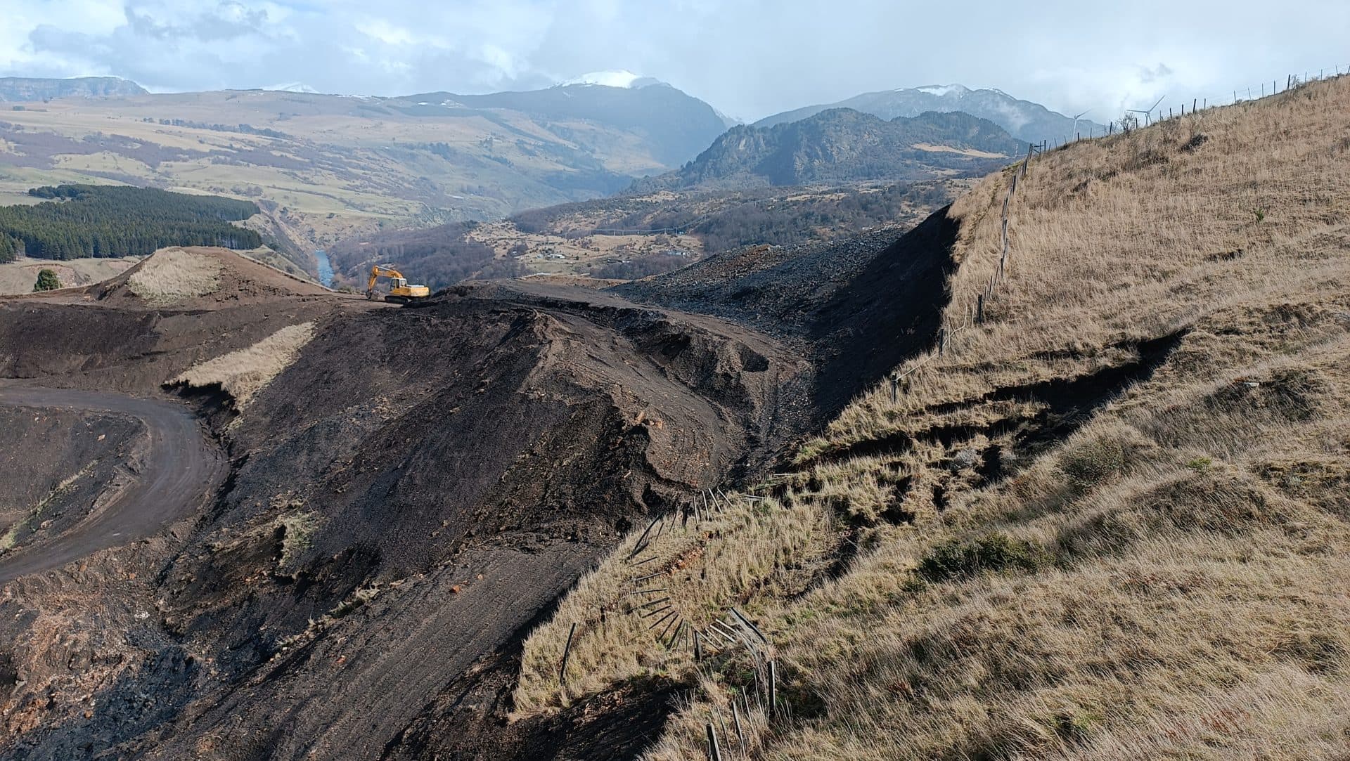Quebrada con erosión activa y ladera intervenida, con la cordillera de fondo, en la Región de Aysén.
